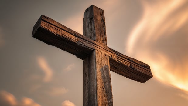 The setting sun casts a warm glow through a large wooden cross photo