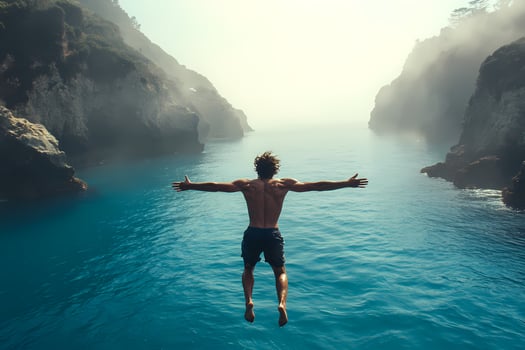 Man diving into ocean between cliffs with open arms photo