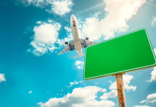 Airplane Flying Over Blank Green Sign in Clear Skies photo
