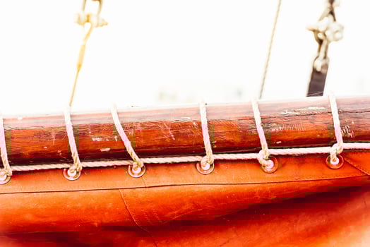 Sailboat mast and ropes with vibrant orange sail creating nautical background photo