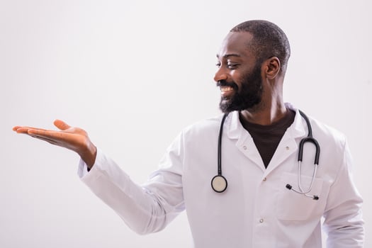 Portrait of cheerful black doctor who is showing palm of hand on gray background. Copy space for your text or advertisement. photo