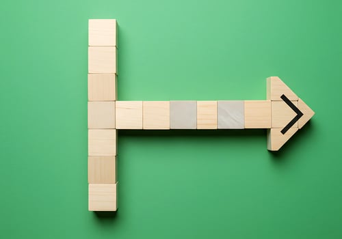 Wooden blocks with arrow pointing to the right on green background photo