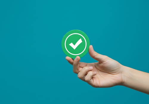 Hand holding green check mark on blue background photo