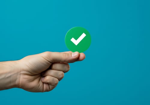 A hand holding a green check mark on a blue background photo
