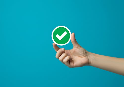 Hand holding green tick mark on blue background photo