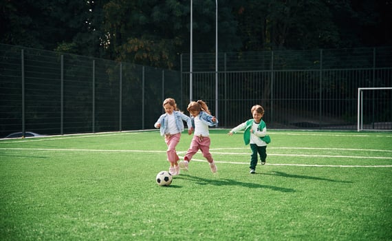 Running ,with ,ball. Kids are having fun on the green soccer field together photo