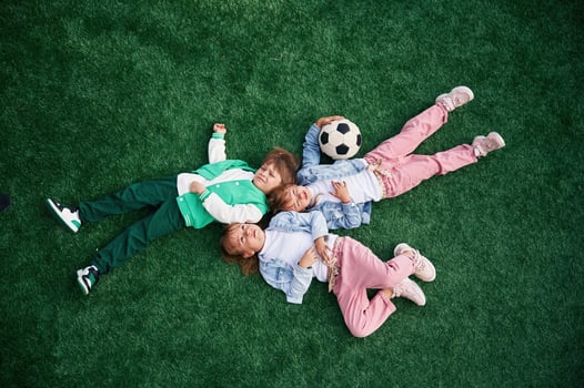 Top view. Lying down. Kids, are having ,fun on the green soccer field together photo