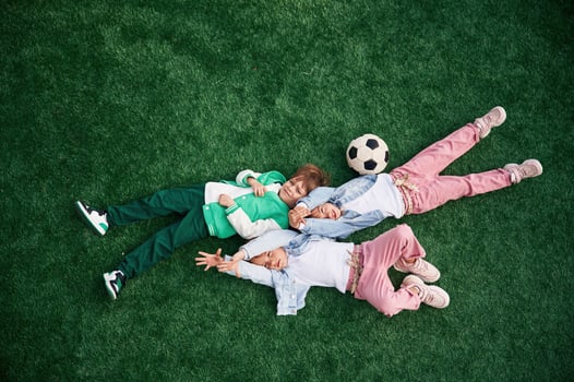 Top view. Lying down. Kids are having, fun ,on the green soccer field together photo