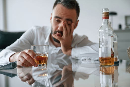 Conception ,of ,addiction. Upset young man drinker alcoholic is indoors photo