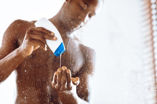Black Man Pouring Shower Gel Washing Body Standing Naked Under Falling Water In Modern Bathroom At Home. Men's Daily Hygiene Routine, Male Beauty Products Concept. Cropped, Selective Focus photo