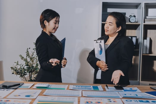 Two businesswomen talking at a desk with papers photo