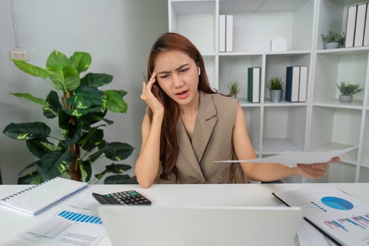 Stress Management and Problem Solving. A woman experiencing stress while evaluating financial reports at her desk. photo