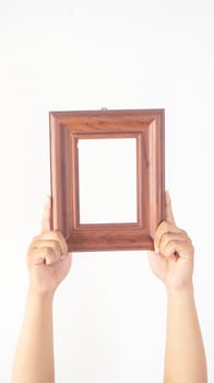 Hand holding empty brown wood photo frame isolated on white background