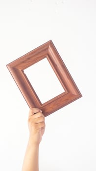 Hand holding brown wooden photo frame isolated on white background