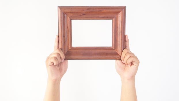 Hand holding blank brown wood photo frame isolated on white background