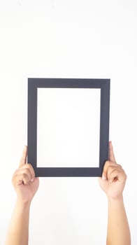 Hand holding black colored wooden picture frame isolated on white background photo