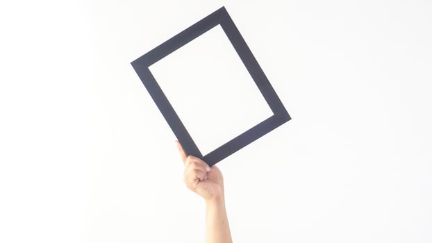 Hand holding simple black colored wooden photo frame isolated on white background