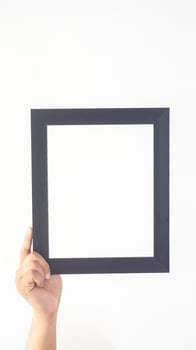 Hand holding black colored wooden photo frame isolated on white background