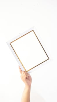 Hand holding blank white colored wooden photo frame isolated on white background