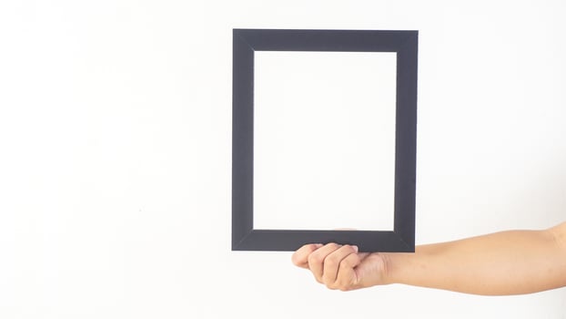 Hand holding empty black colored wooden photo frame isolated on white background