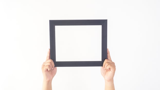 Hand holding black colored wood picture frame isolated on white background photo