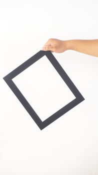 Hand holding empty black colored wooden picture frame isolated on white background photo
