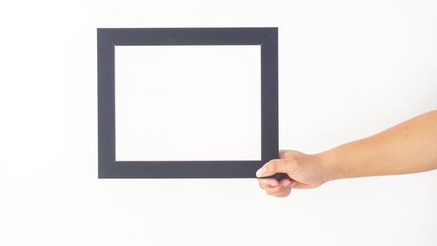 Hand holding blank black colored wooden photo frame isolated on white background