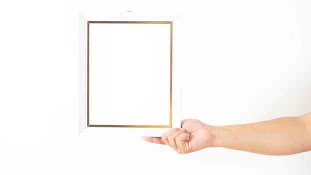 Hand holding white colored wooden photo frame isolated on white background
