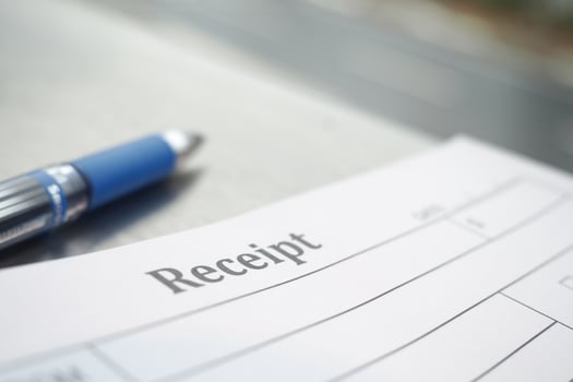 Receipt on a desk with a blue pen nearby during daytime photo