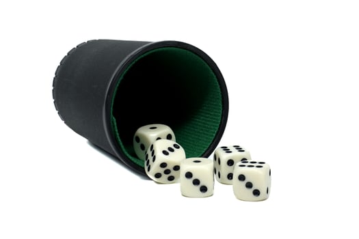 Tipped black dice cup spilling out random assortment of white dice set against a white backdrop photo