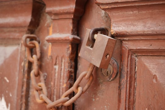 Locked wooden door with a chain and padlock in a rustic setting photo