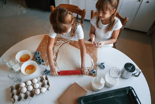 Dough on, the table. Two little girls are preparing food on the kitchen photo