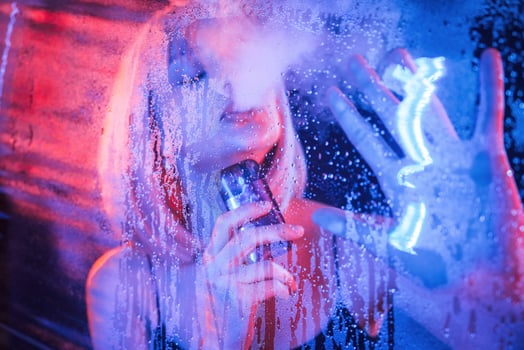 Vaping, holding device. Stylish woman with white hair is behind wet transparent plastic sheet photo