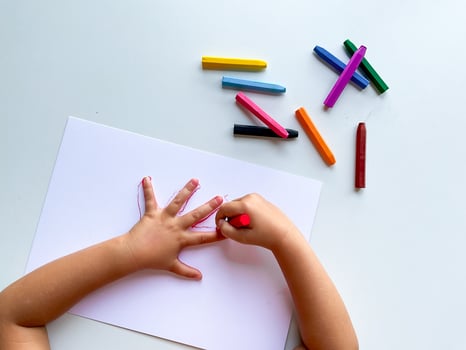 Child drawing with very colorful crayons on white paper. photo
