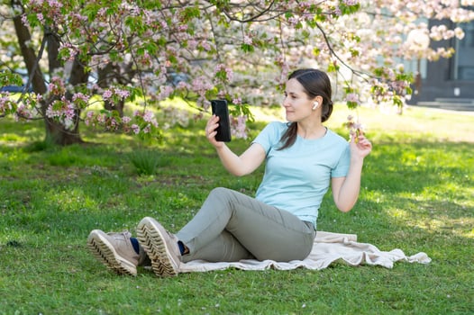 A woman sitting on the grass with her phone photo