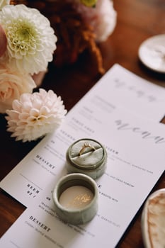 Engagement ring in a box lies on a holiday menu near flowers photo