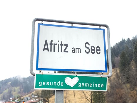 Afritz am see town sign in scenic winter landscape with snowy mountains and trees photo