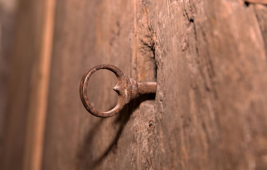 Rusty iron key in weathered wooden door lock with vintage texture photo