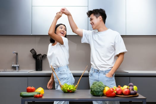 Joyful Japanese Couple Cooking Having Fun, Dancing And Laughing In Modern Kitchen While Preparing Dinner Together. Happy Family Life, Spouses Enjoying Meal Preparation Together. photo