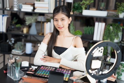 Asia woman beauty influencer makeup artist live streaming makeup tutorial on smartphone for social media photo