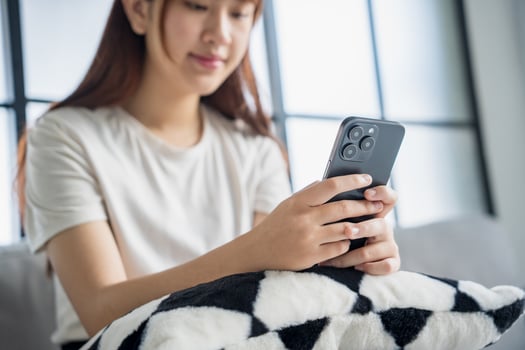 a woman sitting on a couch holding a cell phone. photo