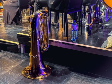 Orchestra tuba at rest beside musicians on stage during concert performance photo
