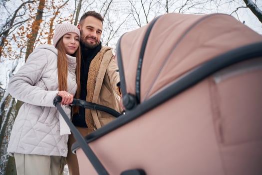 Parents, with pram. Lovely couple have a walk in the winter forest photo