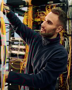 Black clothes. Young man is working with internet equipment and wires in server room photo