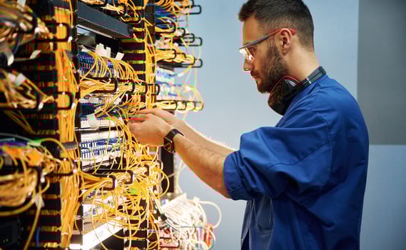 Side view. Young, man, is working with internet equipment and wires in server room photo