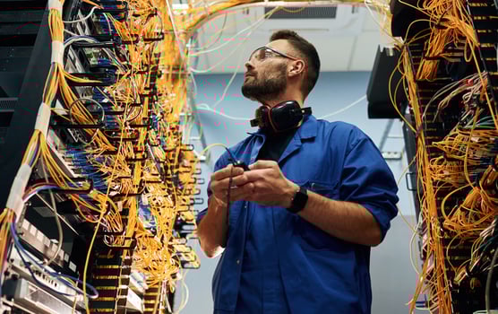 View from ,,below. Young man is working with internet equipment and wires in server room photo