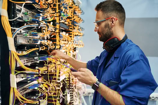 Signal ,stability measured by device. Young man is working with internet equipment and wires in server room photo