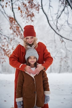 Standing and ,posing. Mother, and her daughter is on the winter meadow and forest photo