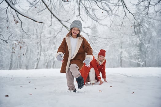Girl is running, front view. Mother, and ,her daughter is on the winter meadow and forest photo