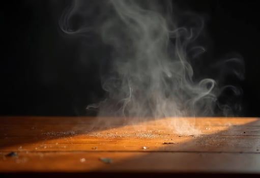 Rising Vapor On Wooden Tabletop With Light Beam Against A Black Background photo
